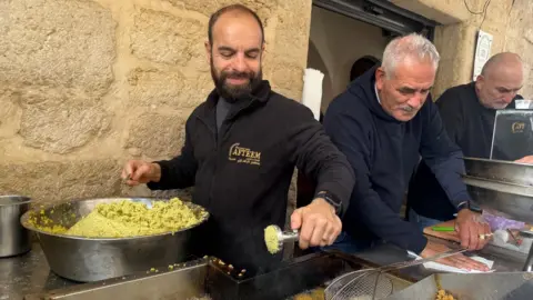 Alaa Salameh smiles as he makes falafel