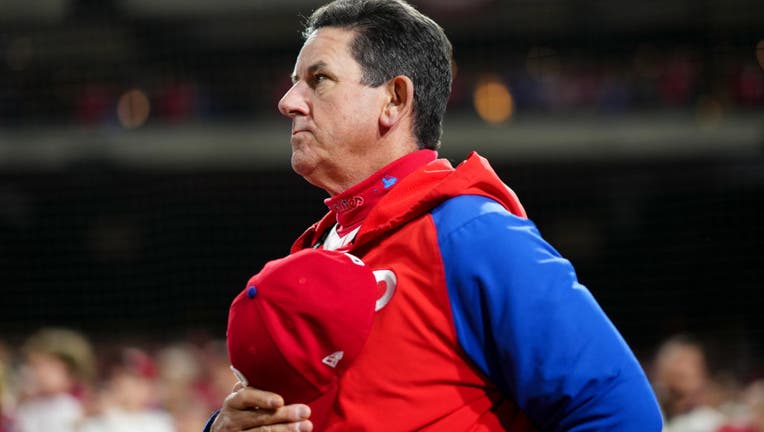 Philadelphia Phillies Manager Rob Thompson in a blue and red Phillies pullover holding a red Phillies cap to his chest with his right hand.
