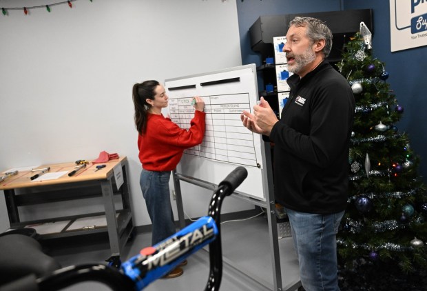 Gene Kaschak gives directions while Danielle Kennon takes notes on the board during the Manufacturers Resource Center's annual Santa's Standard Workshop on Wednesday, Dec. 10, 2025, in Upper Macungie Township. Workers from Just Born, Lutron, Northeast Products & Services and Ocean Spray came together to assemble bicycles for Community Bike Works youth while learning lean manufacturing principles. (Amy Shortell/The Morning Call)