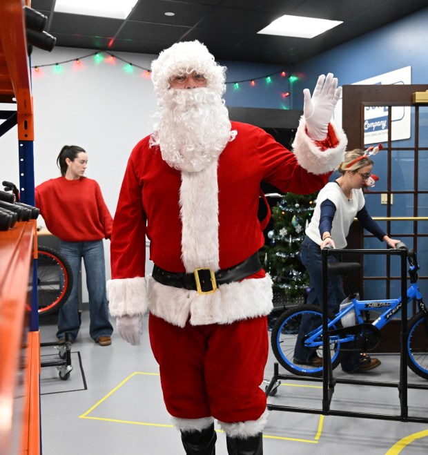 Santa watches over volunteers as they build bicycles during the Manufacturers Resource Center's annual Santa's Standard Workshop on Wednesday, Dec. 10, 2025, in Upper Macungie Township. Workers from Just Born, Lutron, Northeast Products & Services and Ocean Spray came together to assemble the bicycles for Community Bike Works youth while learning lean manufacturing principles. (Amy Shortell / The Morning Call)