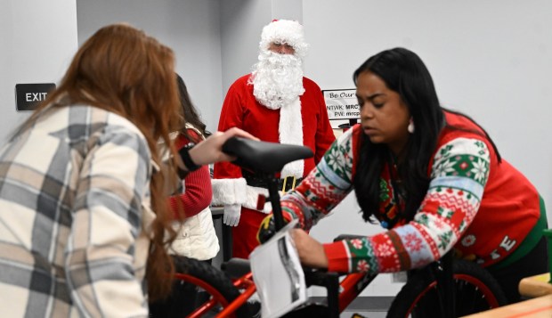 Santa watches over volunteers as they build bicycles during the Manufacturers Resource Center's annual Santa's Standard Workshop on Wednesday, Dec. 10, 2025, in Upper Macungie Township. Workers from Just Born, Lutron, Northeast Products & Services and Ocean Spray came together to assemble the bicycles for Community Bike Works youth while learning lean manufacturing principles. (Amy Shortell / The Morning Call)