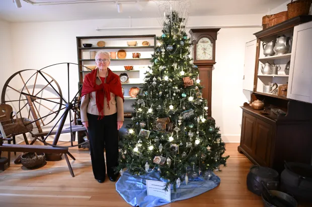 Sharon Donchez, the longtime Trees of Historic Bethlehem co-chair and Historic Bethlehem Museums & Sites' 2025 volunteer of the year, stands next to the waterworks tree she designed Sunday, Dec. 7, 2025, at the Moravian Museum of Bethlehem in the 1741 Gemeinhaus in Bethlehem. (Amy Shortell/The Morning Call)