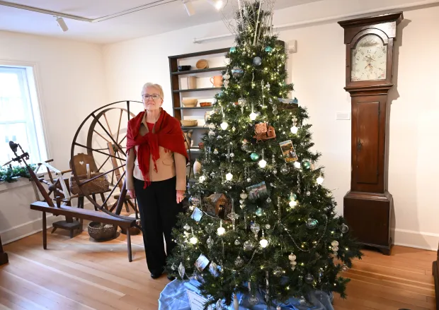 Sharon Donchez, the longtime Trees of Historic Bethlehem co-chair and Historic Bethlehem Museums & Sites' 2025 volunteer of the year, stands next to the waterworks tree she designed Sunday, Dec. 7, 2025, at the Moravian Museum of Bethlehem in the 1741 Gemeinhaus in Bethlehem. (Amy Shortell/The Morning Call)