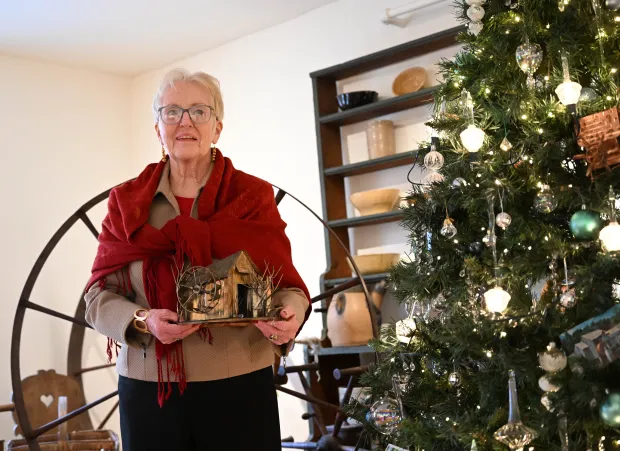 Sharon Donchez, the longtime Trees of Historic Bethlehem co-chair and Historic Bethlehem Museums & Sites' 2025 volunteer of the year, holds an ornament next to the waterworks tree she designed Sunday, Dec. 7, 2025, at the Moravian Museum of Bethlehem in the 1741 Gemeinhaus in Bethlehem. (Amy Shortell/The Morning Call)