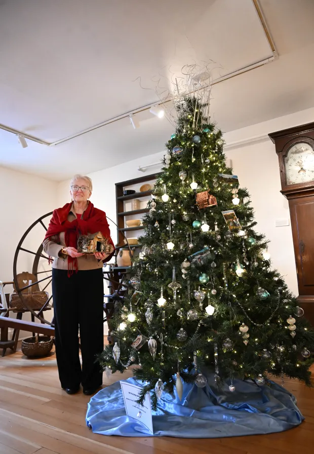 Sharon Donchez, the longtime Trees of Historic Bethlehem co-chair and Historic Bethlehem Museums & Sites' 2025 volunteer of the year, holds an ornament next to the waterworks tree she designed Sunday, Dec. 7, 2025, at the Moravian Museum of Bethlehem in the 1741 Gemeinhaus in Bethlehem. (Amy Shortell/The Morning Call)