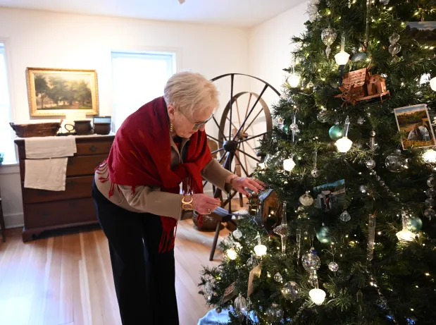 Sharon Donchez, the longtime Trees of Historic Bethlehem co-chair and Historic Bethlehem Museums & Sites' 2025 volunteer of the year, adjusts an ornament next to the waterworks tree she designed Sunday, Dec. 7, 2025, at the Moravian Museum of Bethlehem in the 1741 Gemeinhaus in Bethlehem. (Amy Shortell/The Morning Call)