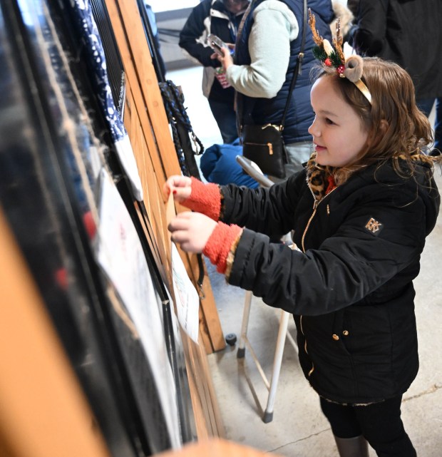 Avrianna Ross,6, of Whitehall, hangs her picture outside of police horse Casper's stall during the Holiday with the Horses open house Sunday, Dec. 7, 2025, at the Bethlehem mounted police unit's barn. (Amy Shortell/The Morning Call)