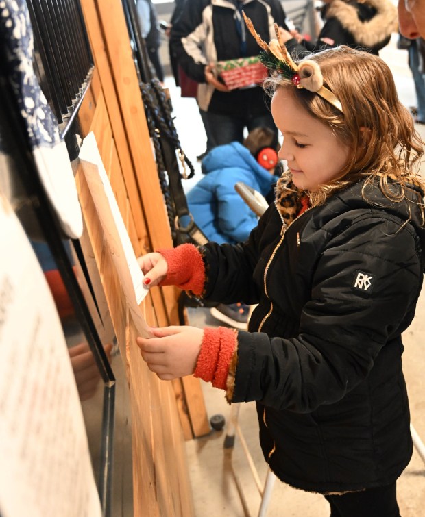 Avrianna Ross,6, of Whitehall, hangs her picture outside of police horse Casper's stall during the Holiday with the Horses open house Sunday, Dec. 7, 2025, at the Bethlehem mounted police unit's barn. (Amy Shortell/The Morning Call)
