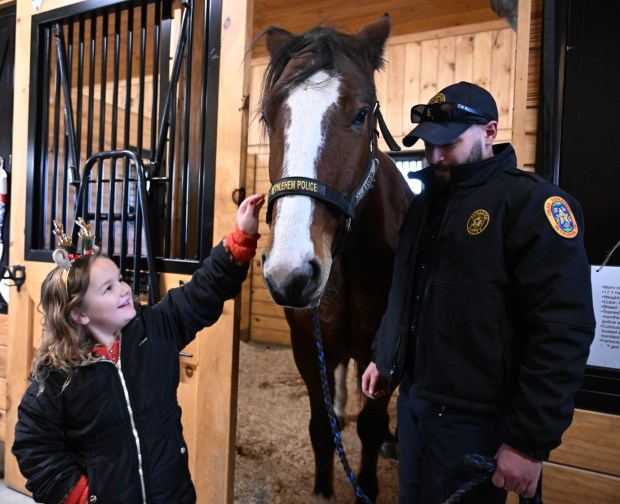 Avrianna Ross,6, of Whitehall, pets Bethlehem police horse Casper during the Holiday with the Horses open house Sunday, Dec. 7, 2025, at the Bethlehem mounted police unit's barn. (Amy Shortell/The Morning Call)