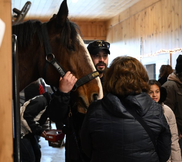 Bethlehem patrol officer Wilfredo Cruz cuddles with Casper during the Holiday with the Horses open house Sunday, Dec. 7, 2025, at the Bethlehem mounted police unit's barn. (Amy Shortell/The Morning Call)