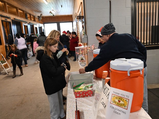 Volunteers serve cider Sunday during the Holiday with the Horses open house Sunday, Dec. 7, 2025, at the Bethlehem mounted police unit's barn. (Amy Shortell/The Morning Call)