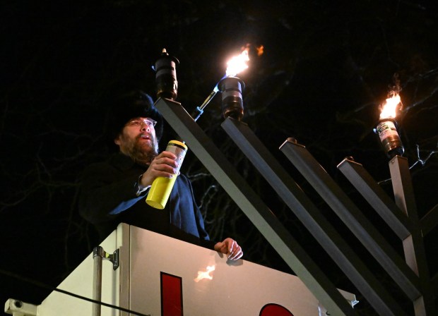 Rabbi Yaacov Halperin and Bethlehem firefighters light three candles Monday, Dec. 15, 2025, on a Hanukkah menorah at Payrow Plaza in Bethlehem. Monday was the second night of the eight-day Jewish Festival of Lights. The third candle is the shamash, a ninth candle that is used to light other candles. (Amy Shortell/The Morning Call)