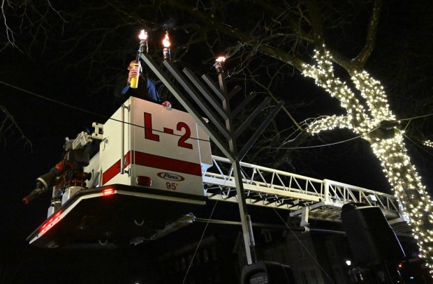 Rabbi Yaacov Halperin and Bethlehem firefighters light three candles Monday, Dec. 15, 2025, on a Hanukkah menorah at Payrow Plaza in Bethlehem. Monday was the second night of the eight-day Jewish Festival of Lights. The third candle is the shamash, a ninth candle that is used to light other candles. (Amy Shortell/The Morning Call)