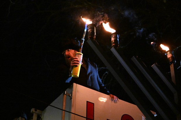 Rabbi Yaacov Halperin and Bethlehem firefighters light three candles Monday, Dec. 15, 2025, on a Hanukkah menorah at Payrow Plaza in Bethlehem. Monday was the second night of the eight-day Jewish Festival of Lights. The third candle is the shamash, a ninth candle that is used to light other candles. (Amy Shortell/The Morning Call)