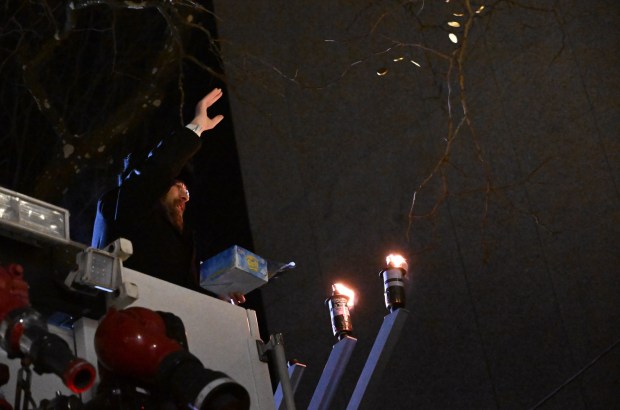 Rabbi Yaacov Halperin throws chocolate gold coins, known as gelt, from the bucket of a fire truck after lighting three candles Monday, Dec. 15, 2025, on a Hanukkah menorah at Payrow Plaza in Bethlehem. Monday was the second night of the eight-day Jewish Festival of Lights.  (Amy Shortell/The Morning Call)