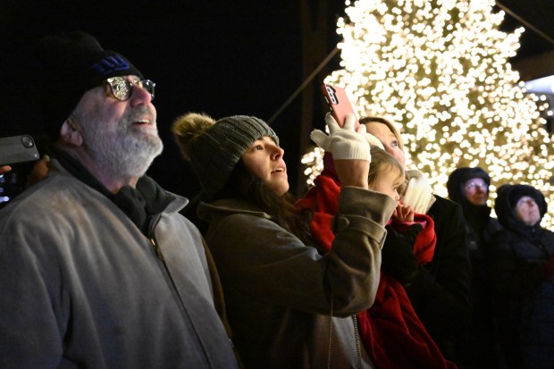 The crowd watches as Rabbi Yaacov Halperin and Bethlehem firefighters light three candles Monday, Dec. 15, 2025, on a Hanukkah menorah at Payrow Plaza in Bethlehem. Monday was the second night of the eight-day Jewish Festival of Lights. The third candle is the shamash, a ninth candle that is used to light other candles. (Amy Shortell/The Morning Call)