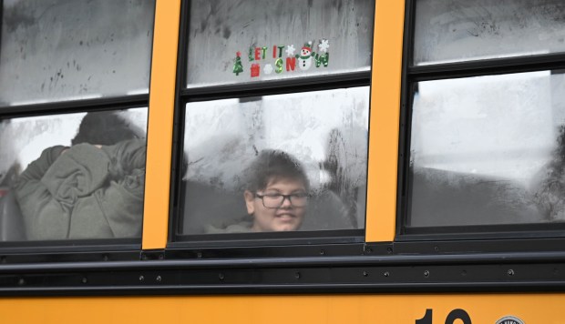 Children peek out bus windows as they arrive with a police escort  Saturday, Dec. 6, 2025, at Target in Allentown during Shop with an Airport Cop hosted by the Lehigh-Northampton Airport Authority Police Department. (Amy Shortell/The Morning Call)