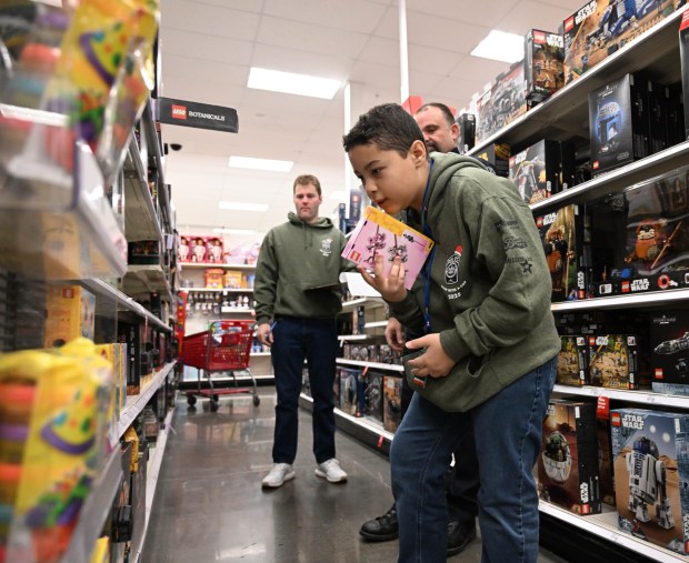 Messiah Santiago shops with Saturday, Dec. 6, 2025, with Officer Adam Gangaware, a Lehigh-Northampton Airport Authority police officer, at Target in Allentown during Shop with an Airport Cop. (Amy Shortell/The Morning Call)