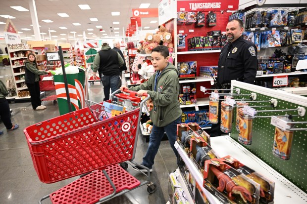 Messiah Santiago shops with Saturday, Dec. 6, 2025, with Officer Adam Gangaware, a Lehigh-Northampton Airport Authority police officer, at Target in Allentown during Shop with an Airport Cop. (Amy Shortell/The Morning Call)