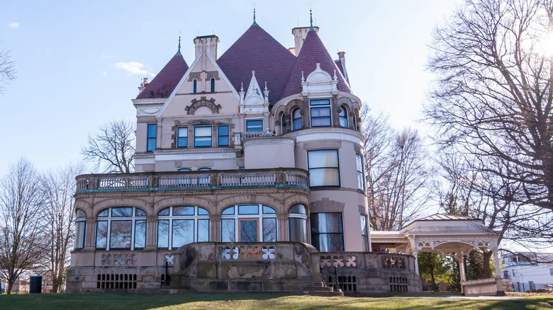 Clayton Mansion in Pittsburgh, a large 1860s building with a maroon roof under a blue sky surrounded by leafless trees