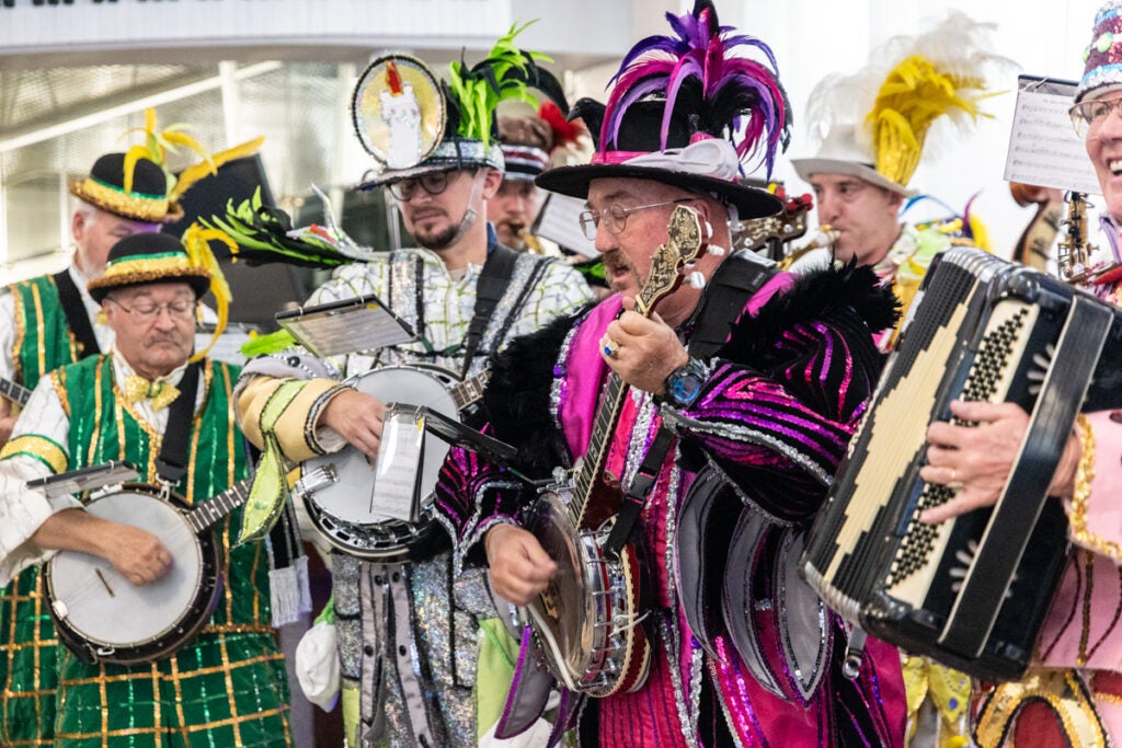 Members of various Mummers clubs’ string bands play their instruments in colorful outfits