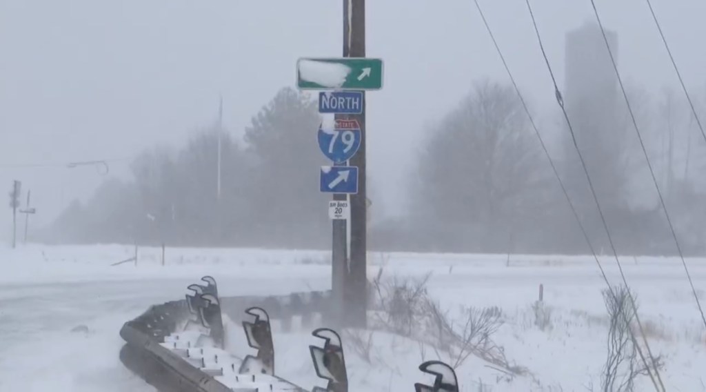 Snow-covered road sign for I-79 North with an arrow pointing right.