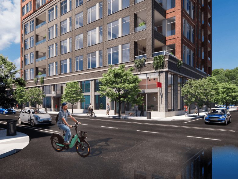 A man rides a bicycle in front of a rendering of a modern multi-story building on a city street with cars and pedestrians nearby.