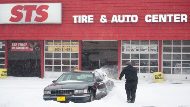 Josh Stess, manager of STS Tire and Auto Center on Lehigh Street in Allentown, cleans off customers' cars during the Blizzard of 2016 on Saturday, Jan. 23, 2016. (Chris Shipley/The Morning Call)