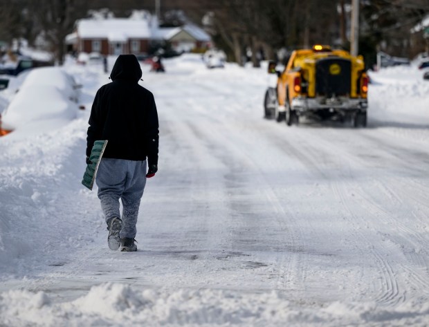 A pedestrian with a shovel walks along a snowy road Monday, Jan. 26, 2026, in Bethlehem after Sunday's storm that dropped more than a foot of snow in some parts of the Lehigh Valley. (April Gamiz/The Morning Call)
