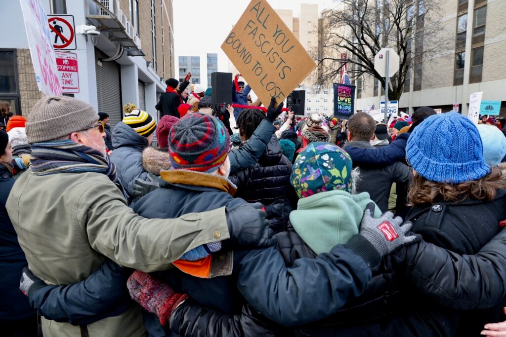 Protesters embrace in a show of unity during a protest against ICE raids on MLK Day in PHiladelphia