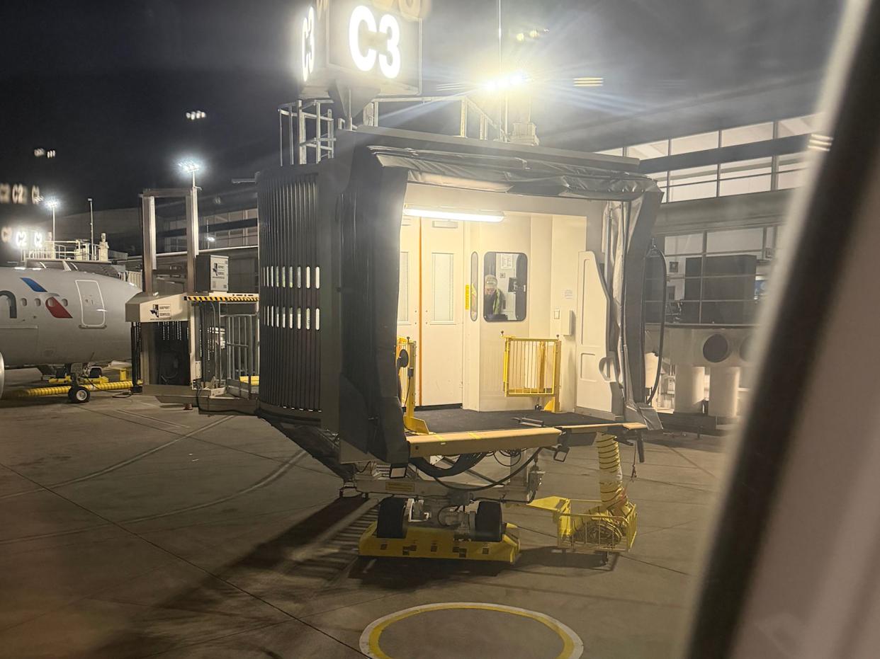 Photo provided by a passenger aboard American Airlines flight 1571 from Dallas-Fort Worth to Harrisburg shows a worker trying to operate a malfunctioning jetbridge. (Shared with WHTM)