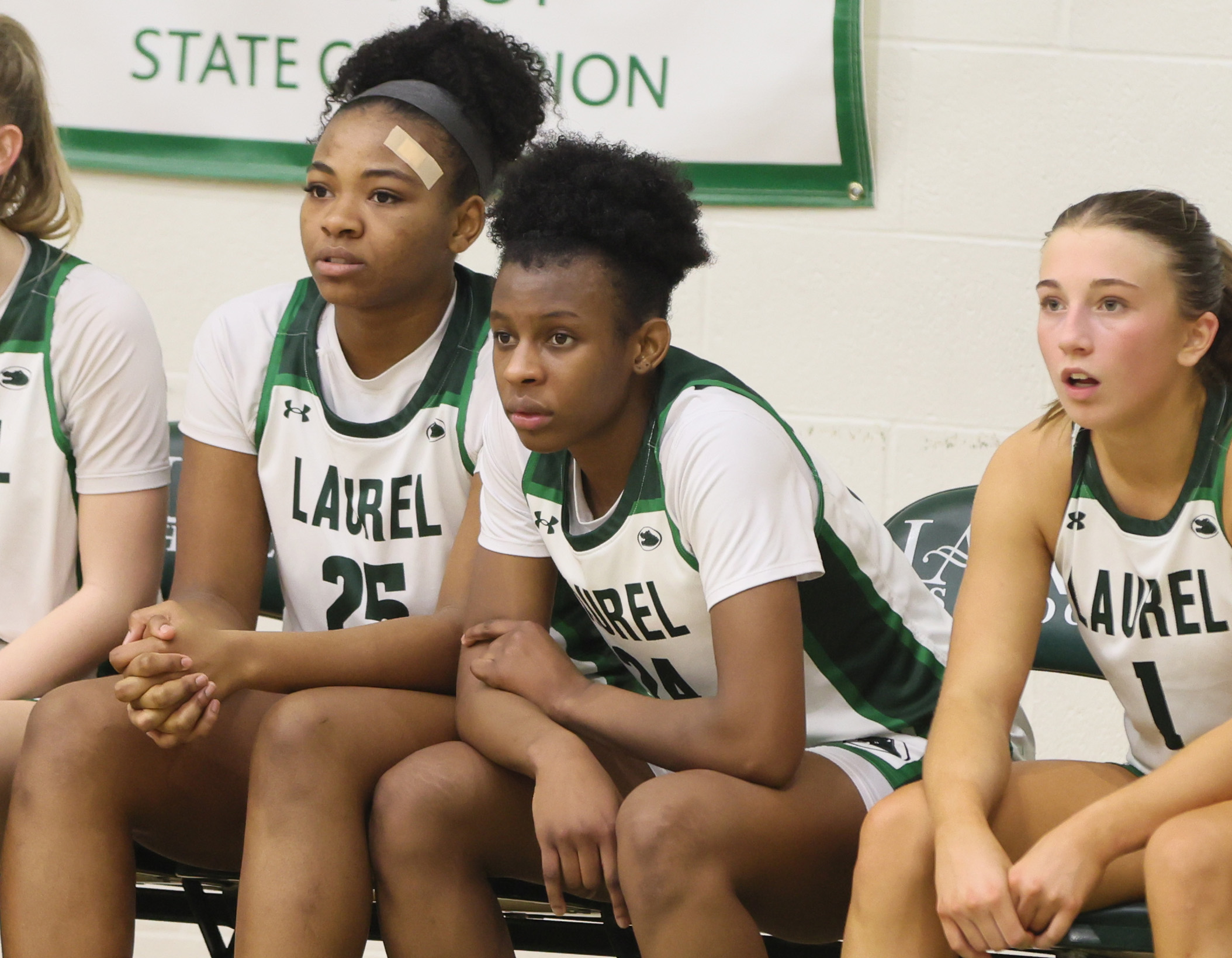 Laurel's Tristan Williams (C) sits on the bench with teammates Laurel's Sydnee Robinson (L) and Laurel's Reese Grammes in the second half.  