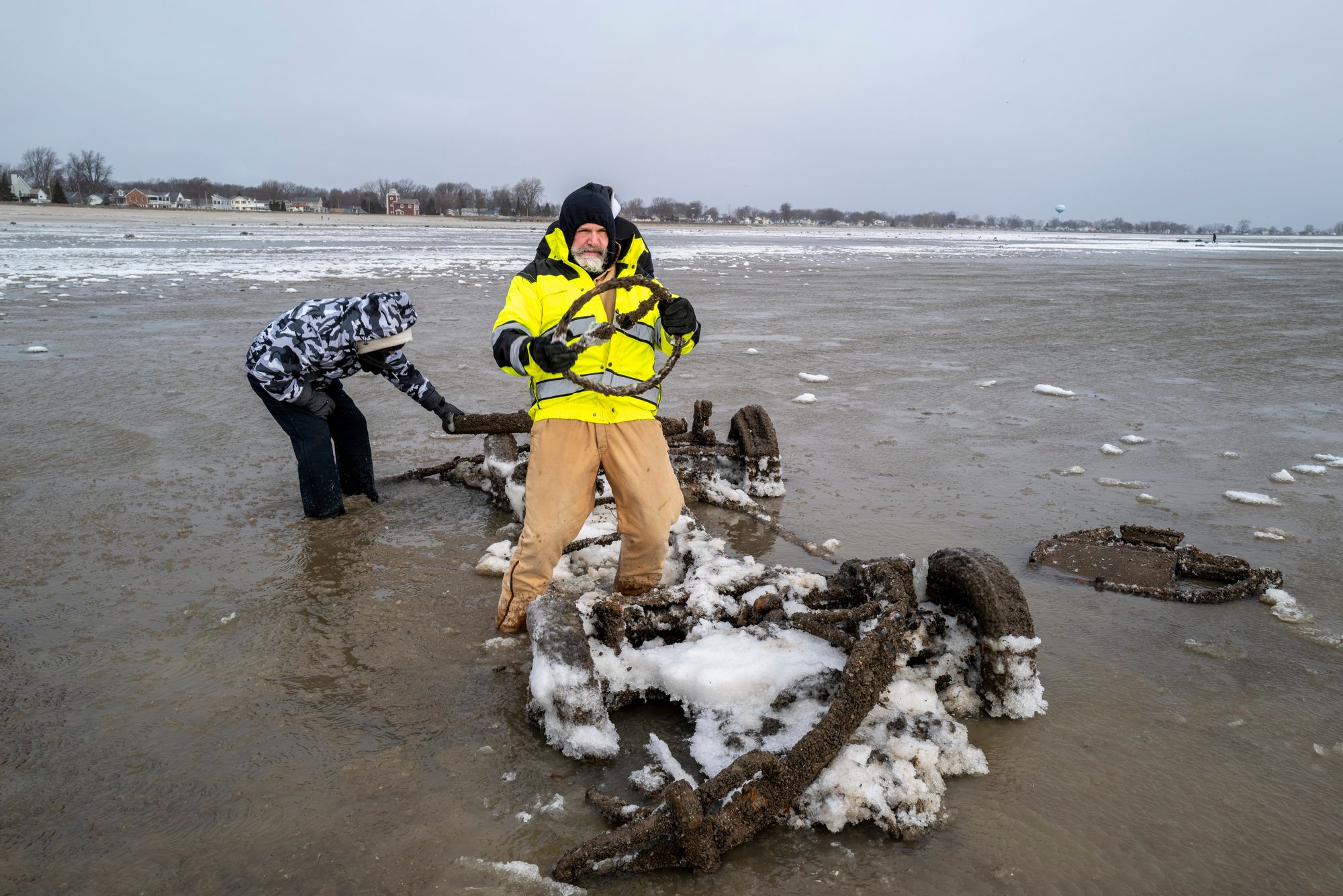 Neil Wakeman, a Luna Pier city council member, holds up a steering wheel as he and friends look over a car that is normally submerged in roughly eight feet of water, about 100 yards off the beach in Luna Pier, Mich., Monday, Dec. 29, 2025