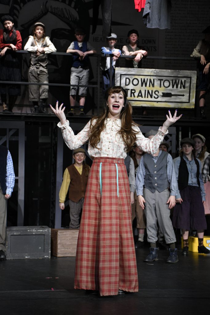students performing in costume on stage