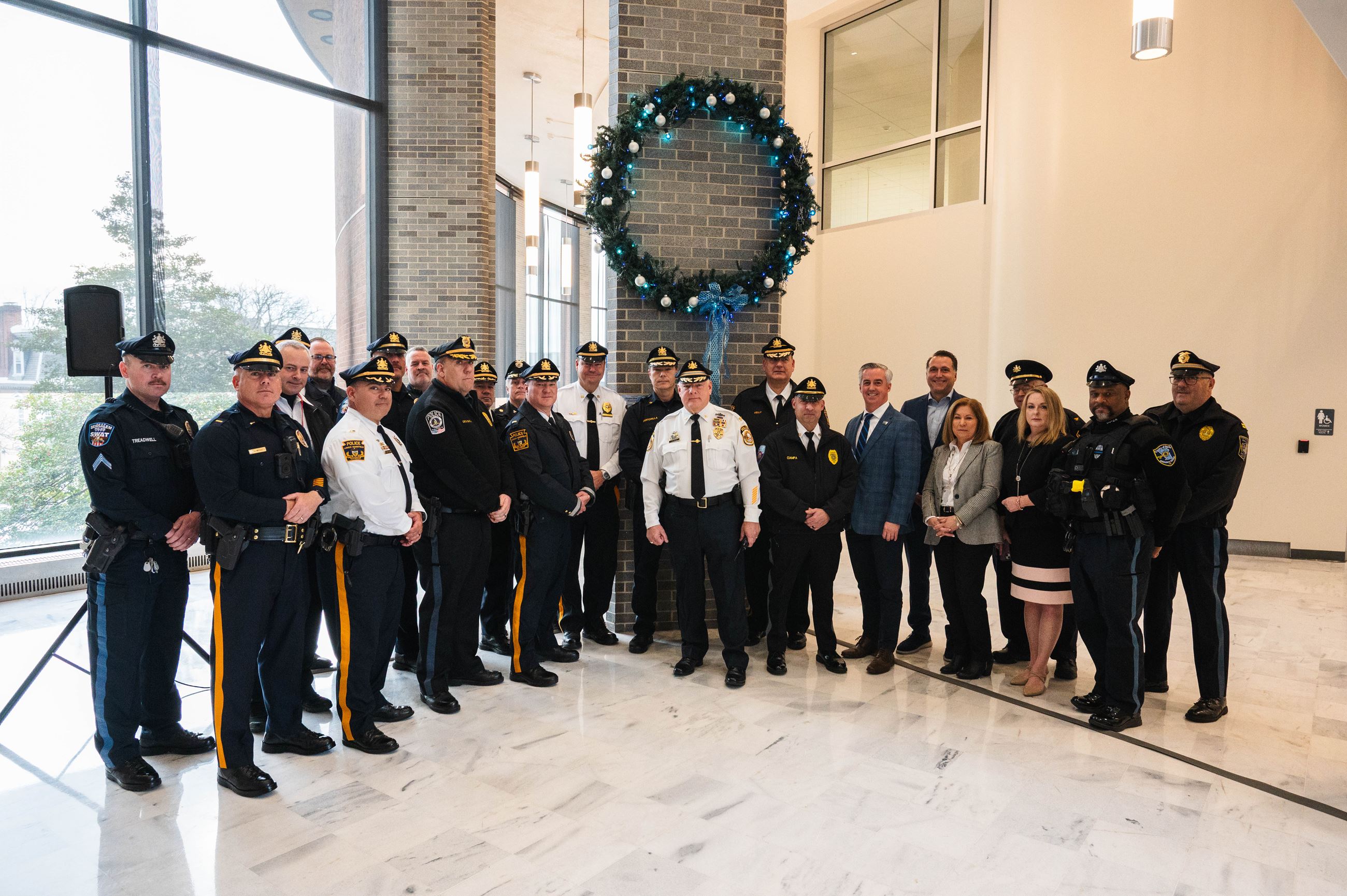 People standing beneath a holiday wreath.