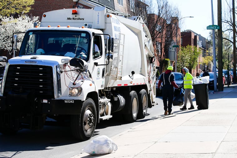 City of Philadelphia sanitation workers pickup trash with a garbage truck along the 1100 block of Lombard Street on Thursday, April 2, 2020.