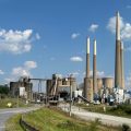 An industrial facility with several large stacks against a blue sky.