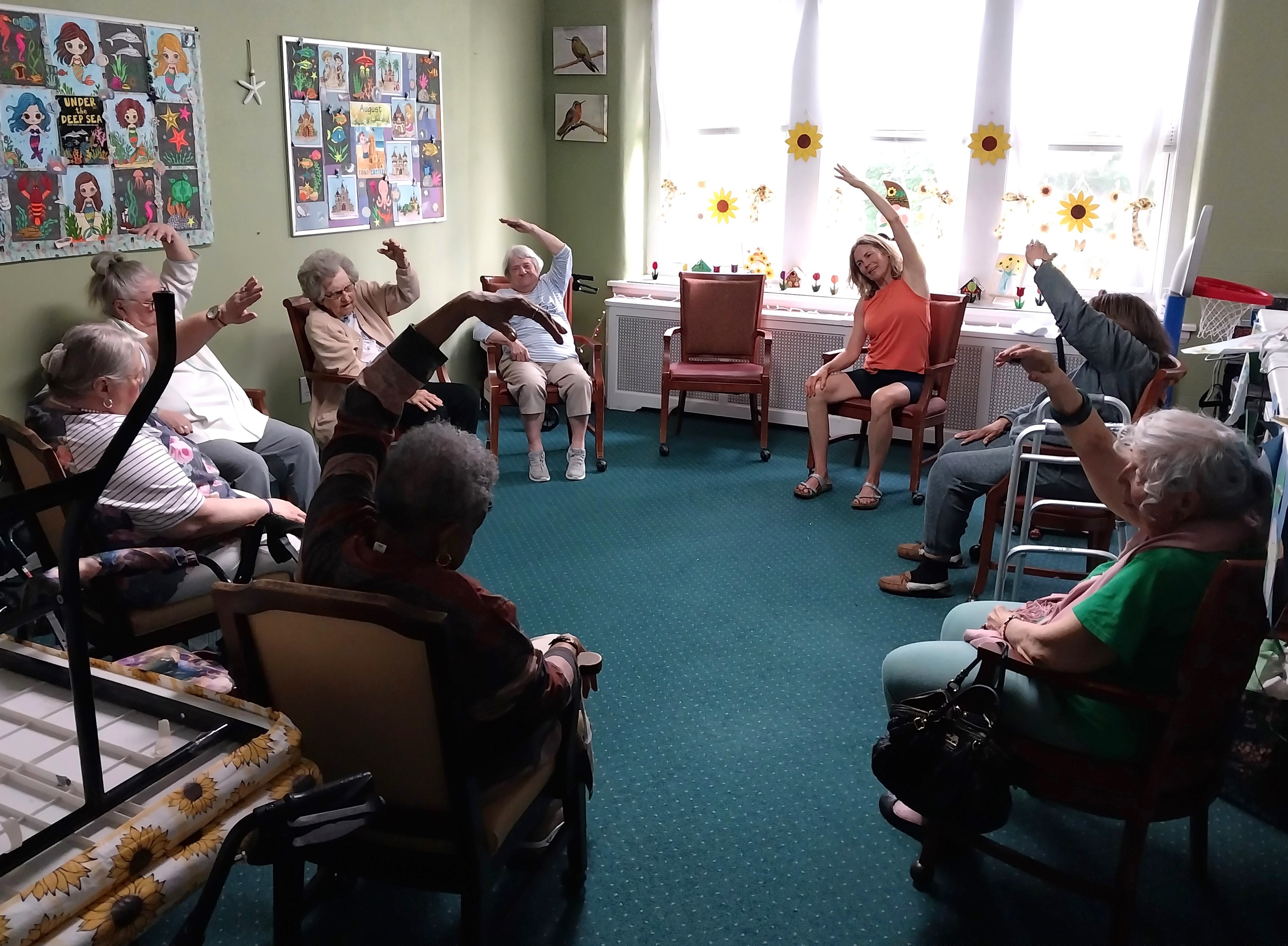 Volunteer Kara helps facilitate some chair stretching as part of...