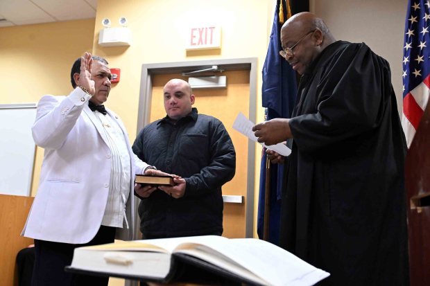 District 5 City Councilman Dr. Rafael Nunez is administered the oath of office by District Justice Alvin Robinson as Nunez's son Schaell Rodriguez holds the Bible during an inauguration ceremony in the Schmidt Training and Technology Center at Reading Area Community College on Monday, Jan. 5, 2026. (BILL UHRICH/READING EAGLE)