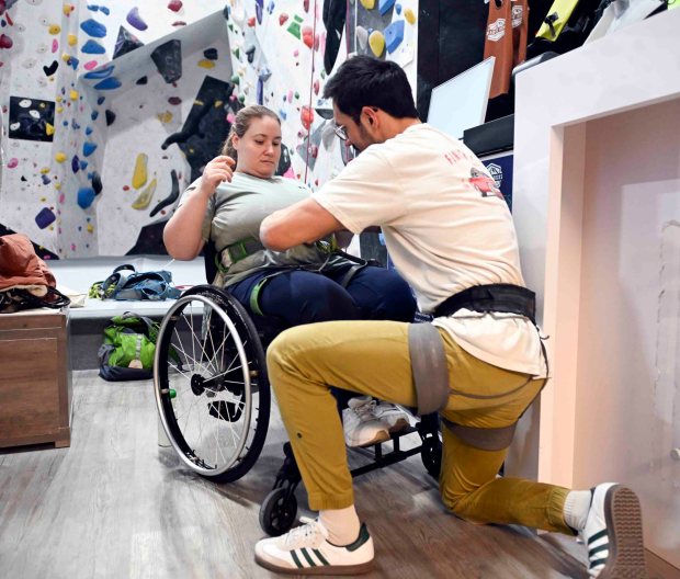 Brandon Anchant, general manager of Reading Rocks, helps secure a climbing harness with Ali DiPiazza during an IM ABLE foundation adaptive rock climbing session at Reading Rocks Climbing and Fitness, 550 George St., Muhlenberg Township. (BILL UHRICH/READING EAGLE)