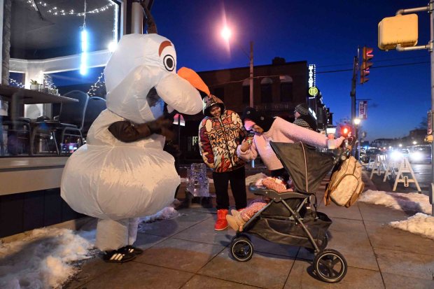 Emily Miller, 19, an Albright College student and employee of Bold Cafe, is dressed as Olaf from the movie "Frozen" and entertains a family at the Ice and Spice Festival in West Reading. (BILL UHRICH/READING EAGLE)