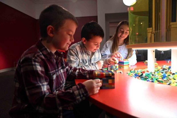 From left, Robbie, 8; Isaac, 9; and Bella Momose, 11, of Leesport put together LEGO bricks during the Towers of Tomorrow with LEGO Bricks exhibit at the Reading Public Museum on Saturday, Jan. 31, 2026. They were at the exhibit with their grandparents Bob and JoAnn Biechy of Birdsboro. (BILL UHRICH/READING EAGLE)