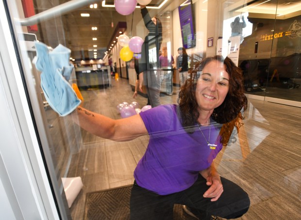 Employee Heather Macavage wipes down the front doors before the grand opening ceremony at the Planet Fitness in Taylor Thursday, January 29, 2026. (SEAN MCKEAG / STAFF PHOTOGRAPHER)