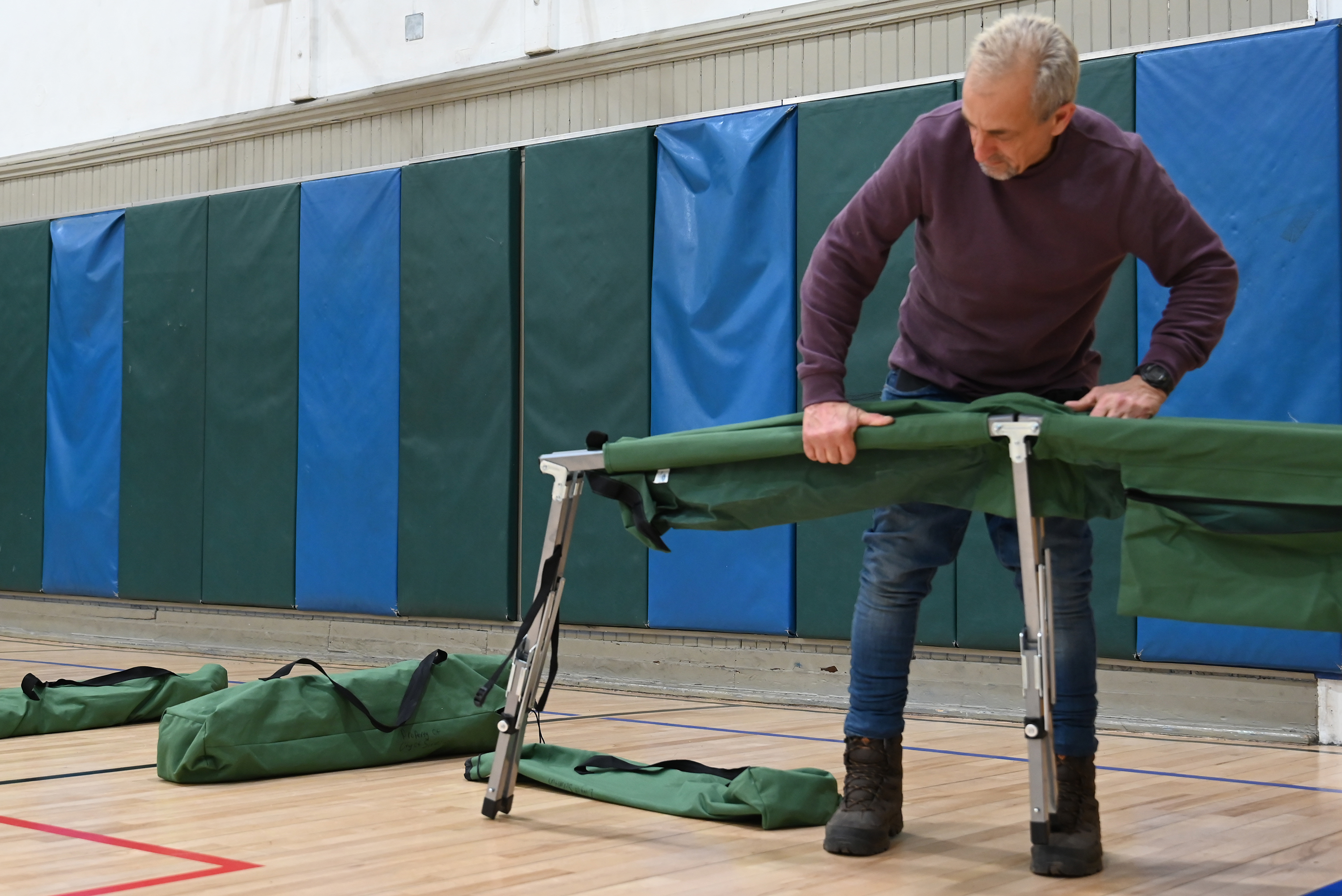 Volunteer and guest Abdullah Gia helps set up cots to...