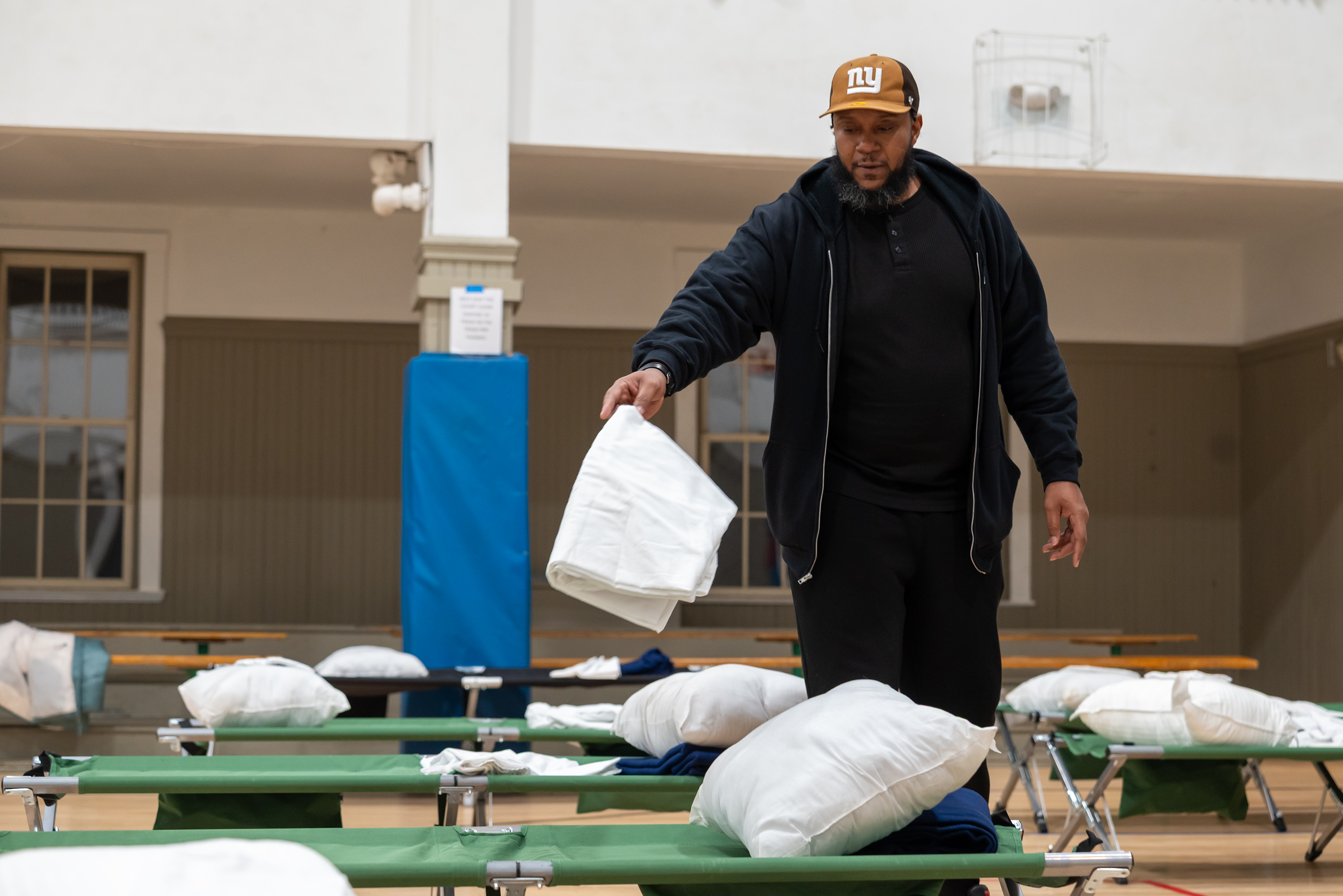 Staff member Raymond Moore sets out bedding at the Code...
