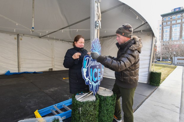 Co-chair of Scranton's Downtown on Ice Festival and Scranton Tomorrow board member Ronda Beemer and Scranton Tomorrow board member Joshua Mast attach a sign to the main tent on N. Washington Ave. in downtown Scranton Friday, January 16, 2026. (SEAN MCKEAG / STAFF PHOTOGRAPHER)