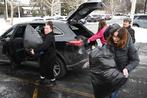 Volunteers help unload Melissa Kennedy's, left, car during the children's clothing drive at the St. Joseph Center in Dunmore, Jan. 16, 2026. Kennedy owns Lil Sweetheart Shop, a consignment store for children's clothing and items, in Dallas. (REBECCA PARTICKA/STAFF PHOTOGRAPHER)