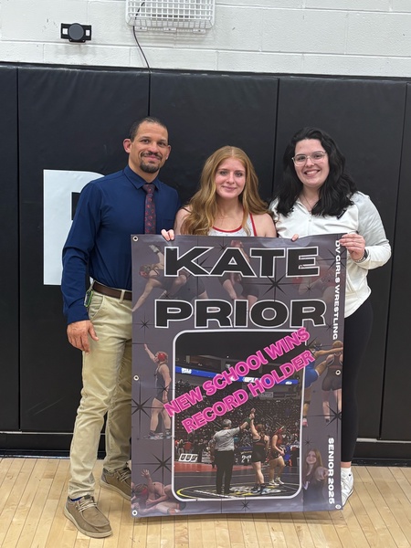 Delaware Valley wrestler Kate Prior, center, holds her school record banner with head coach Evans Bates, left, and assistant coach Karley May. COURTESY OF THOMAS PRIOR
