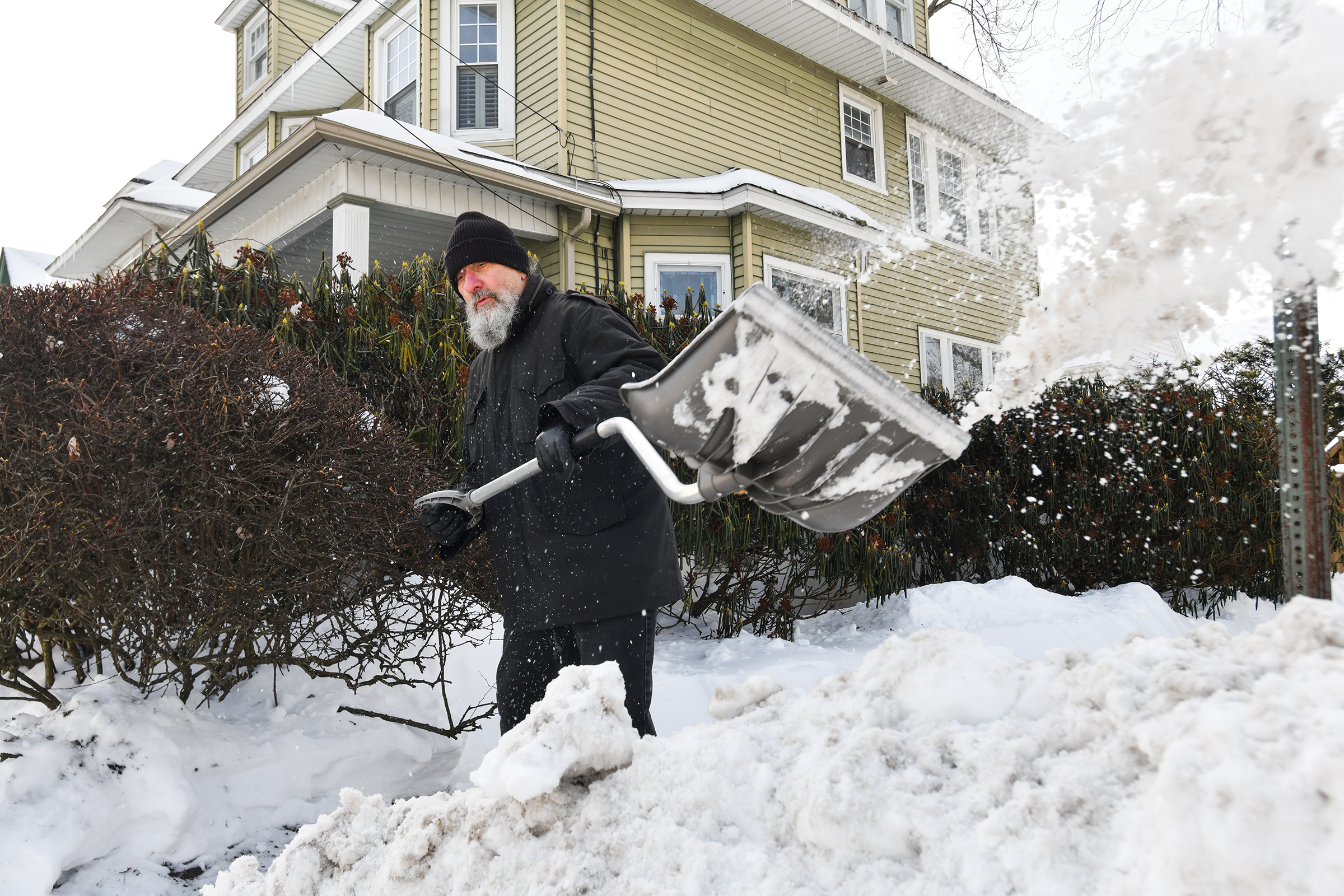 Hill Section resident Steve Corbett shovels the sidewalk that was...
