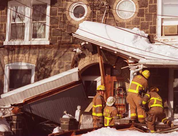 Quakertown firefighters use boards to support portions of a roof still remaining after a row house porch collapsed in the 300 block of Juniper Street in Quakertown after the blizzard of 1996, Jan. 13, 1996. (Doug Benedict/The Morning Call)